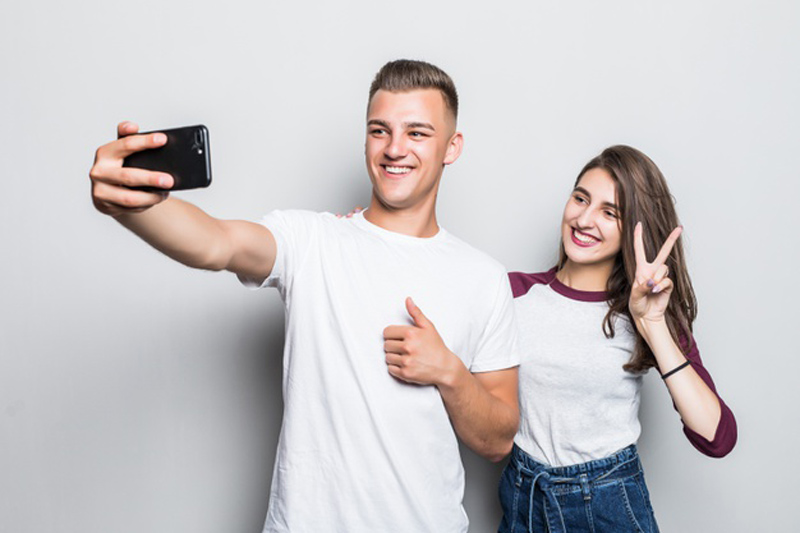 pretty young handsome couple boy girl making selfie their phone isolated white